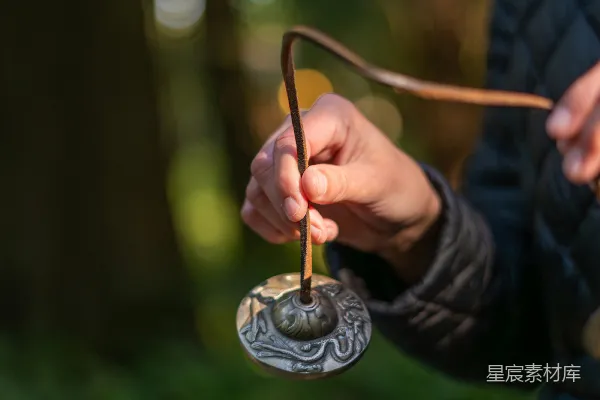 高清摄影 手持一枚雕刻精美的圆形吊坠的人。