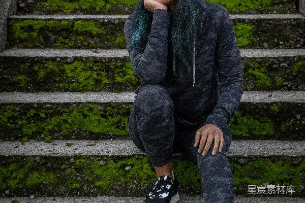 高清摄影 黑夹克男孩坐在混凝土楼梯上，戴着黄色针织帽。