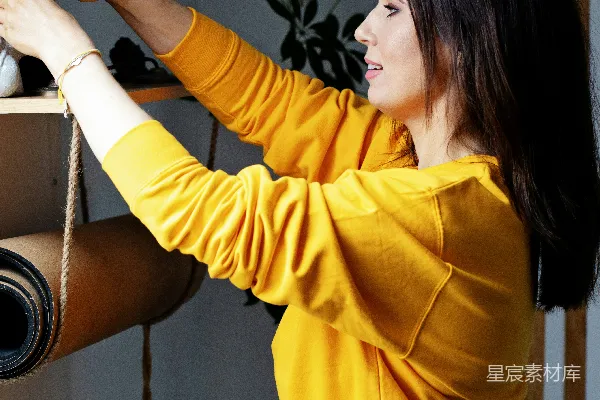 高清摄影 黄色毛衣的女人正在整理带有植物的书架