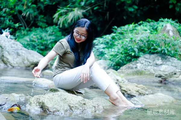 高清摄影 一个女人坐在水边的岩石上
