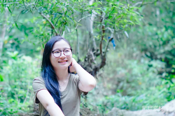 高清摄影 一个女人坐在河边的一块岩石上。