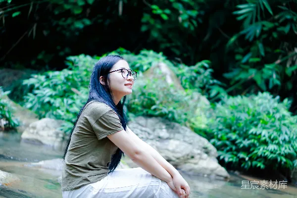 高清摄影 一个戴着眼镜、蓝色头发的女人坐在一块岩石上