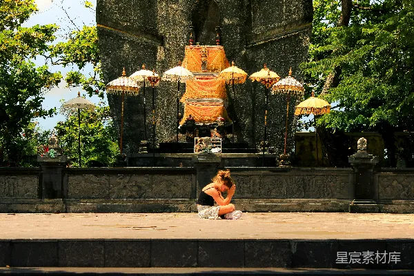 高清摄影 妇女坐在古石 altar 前，有伞。