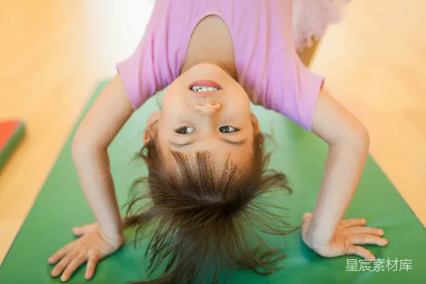 高清摄影 一个女孩 upside down 微笑在绿色的垫子上。