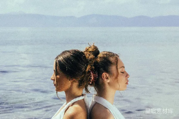 高清摄影 两位妇女站在海滩上，旁边是海洋。