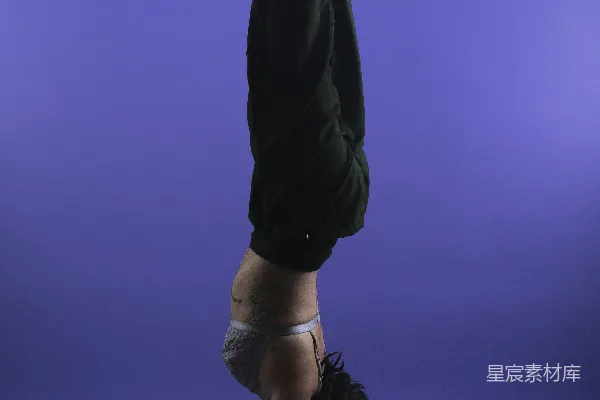 高清摄影 一个穿着紫色背景的手倒立的人
