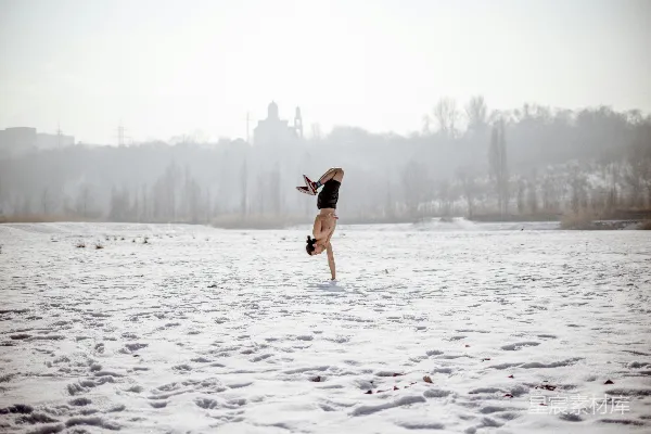 高清摄影 黑色上衣和棕色短裤的女人在雪地上白天跳跃，地面覆盖着积雪。