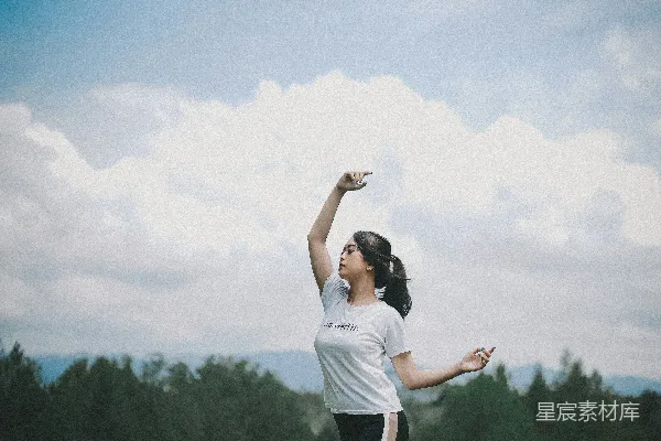 高清摄影 白色上衣的女人站在草地上的田野里，蓝天白云下白天的景象。