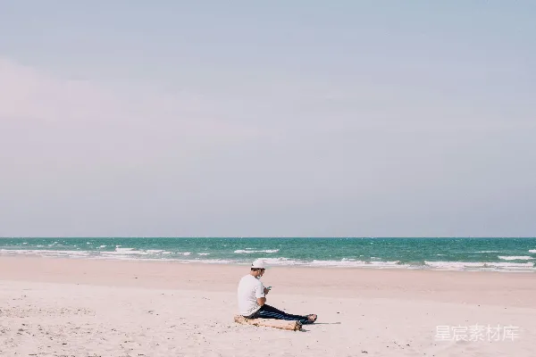 高清摄影 一个男人坐在海边，旁边是海洋。