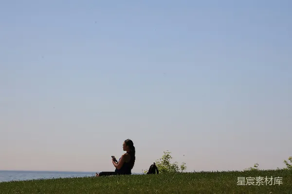 高清摄影 一个女人坐在郁郁葱葱山坡顶部的一处。