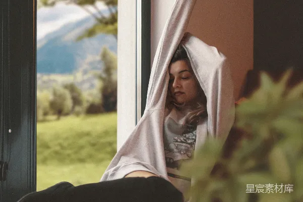 高清摄影 年轻女子在窗户旁拉伸，窗外景色怡人。