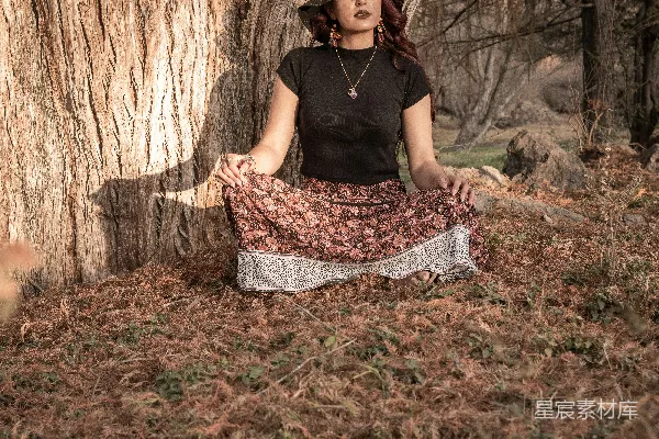 高清摄影 身穿黑色吊带衫和黑白条纹短裙的女人坐在棕色干枯树叶上