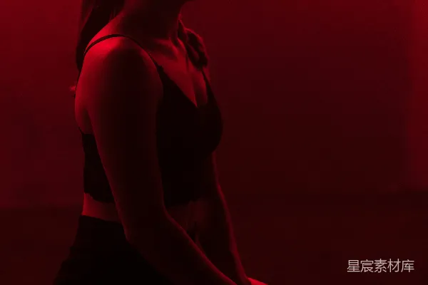 高清摄影 一个女人坐在红色背景前的地板上。