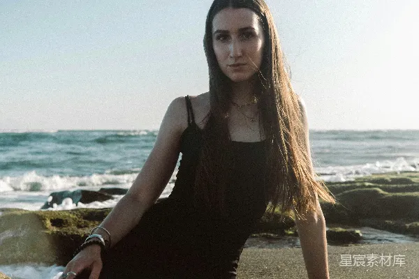 高清摄影 海滩上坐着一位女性，双腿交缠。
