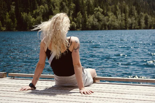 高清摄影 一位妇女坐在码头上看着水面。