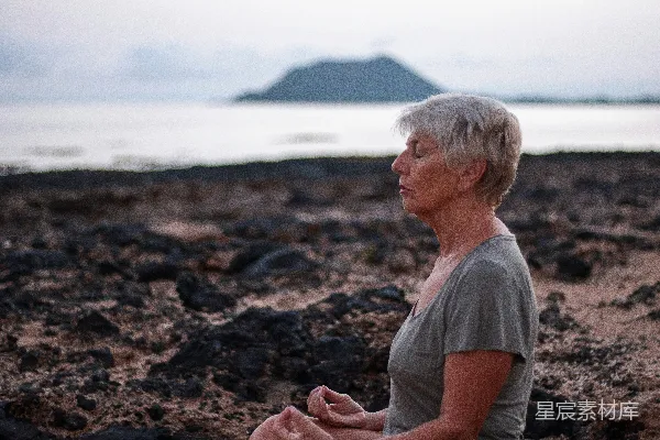 高清摄影 一个女人坐在一块岩石海滩上的莲花坐姿。