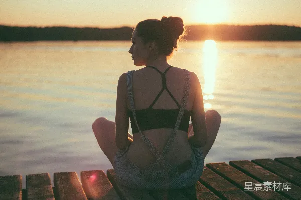 高清摄影 女人坐在棕色木制的码头上，夕阳西下。