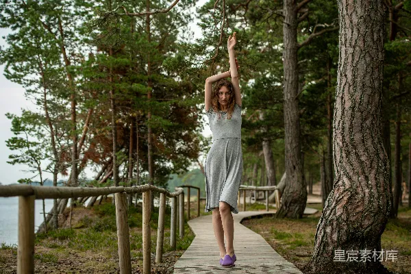 高清摄影 灰衣女子在森林里的木板小径上行走。