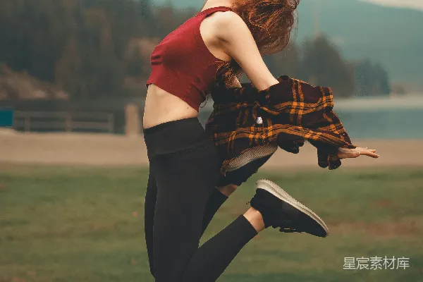 高清摄影 红色上衣和黑色裤子的女人在白天的绿色草地田野上跳跃