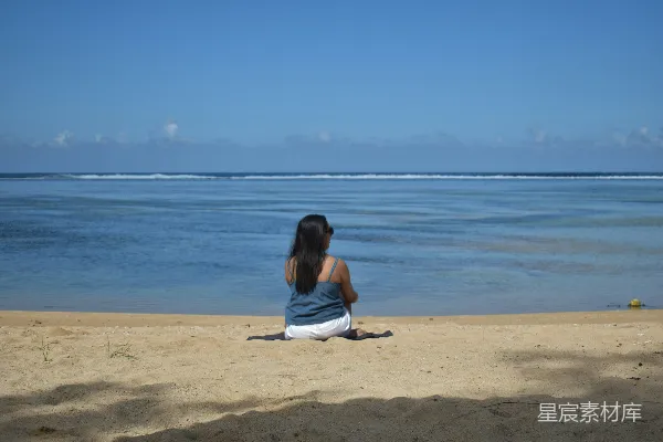 高清摄影 一个女人坐在海滩上，望着大海。