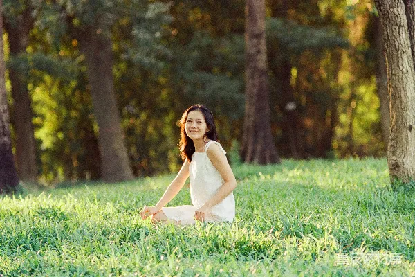 高清摄影 一个穿白色连衣裙的女子坐在草地上。
