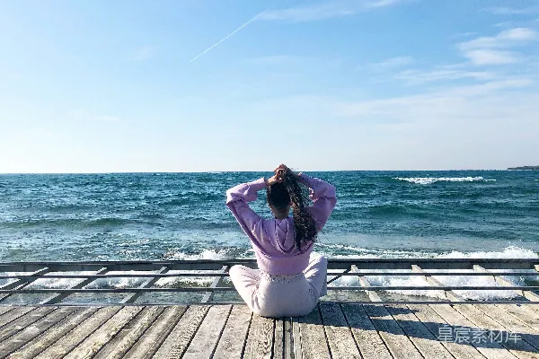 高清摄影 白裤子的女人在木制的码头上坐着，白天的景象