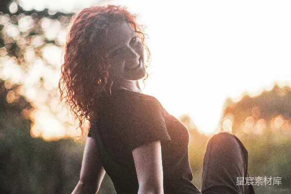 高清摄影 一头红 curly 头发的女人坐在码头上。