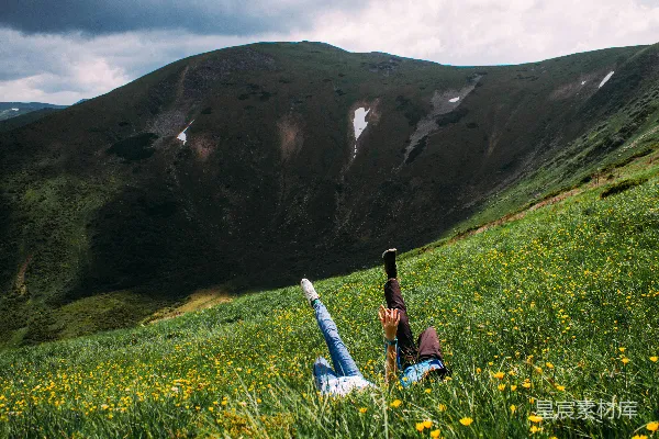 高清摄影 一个人在田野中躺着，背景是山。