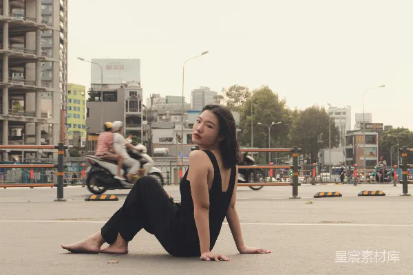 高清摄影 一个女人坐在地上，背景中有摩托车。