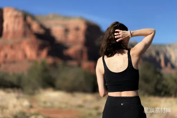 高清摄影 一个穿着黑色运动bra上衣和紧身 leggings 的女性站在前面。