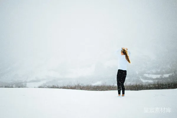 高清摄影 白天一名妇女站在覆盖着雪的空地上