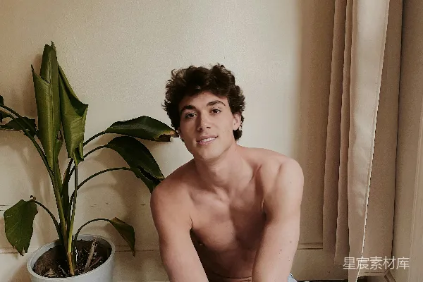 高清摄影 裸胸的男人坐在灰色的沙发椅上，穿着蓝色的牛仔裤