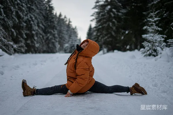 高清摄影 橙色夹克和黑色长裤的女人坐在覆盖着白雪的地面上，白天。