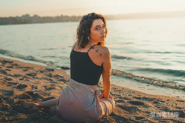 高清摄影 黑色上衣和粉色长裤的女人坐在海滩边缘的白天坐在海滩边