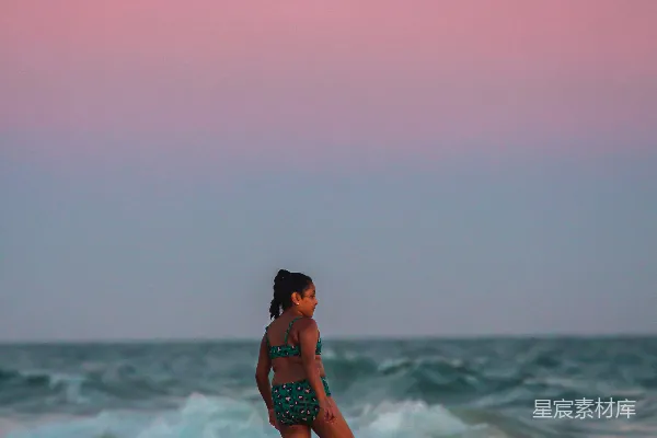高清摄影 海滩上站立着一位妇女，靠近大海。