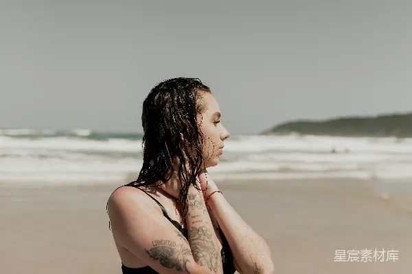 高清摄影 海滩上站着一位妇女，旁边是海洋。