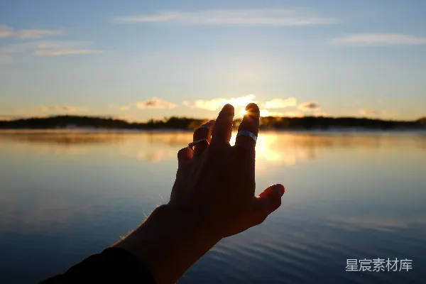 高清摄影 一个人伸手去拿放在水面之上的太阳