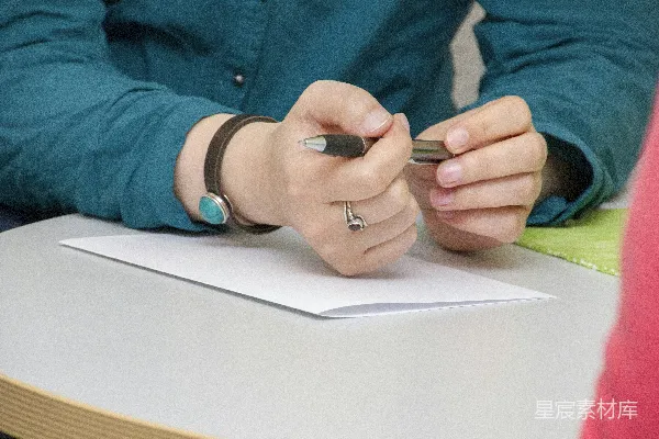 高清摄影 一个人坐在桌子旁在一张纸上写着。