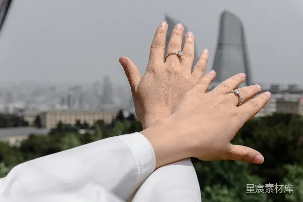 高清摄影 两只戴戒指的手 against a city skyline.