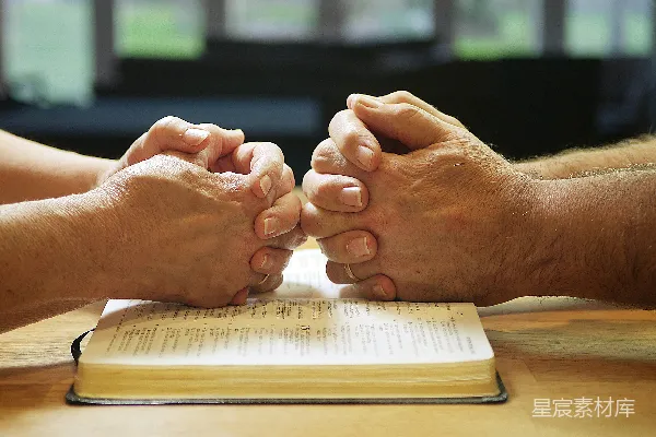 高清摄影 两个人手牵手坐在一张桌子旁，旁边放着一本书