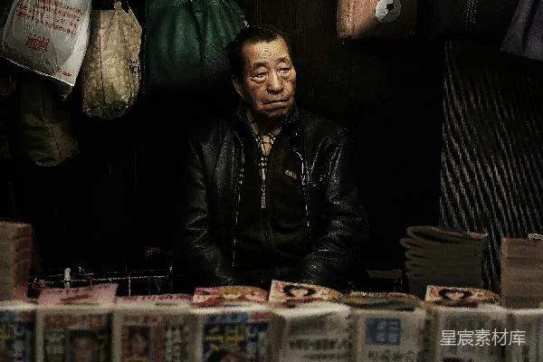 高清摄影 一个男人坐在桌子前，桌子上堆满了报纸。