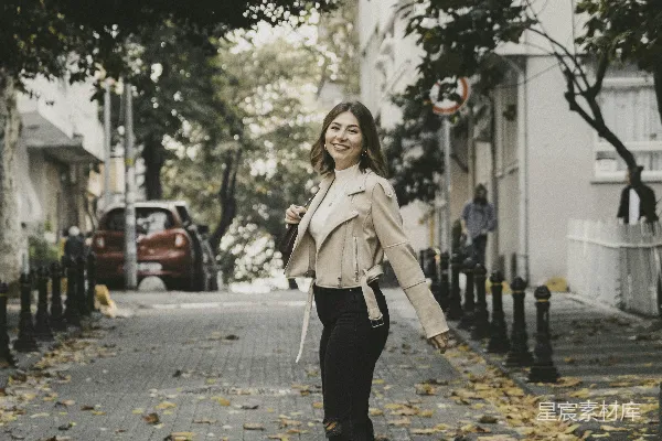 高清摄影 一个女人走在街道旁边，旁边是树木。