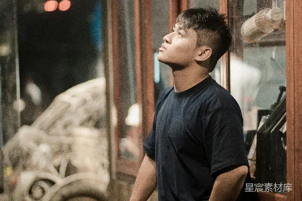 高清摄影 一个男人仰头看着上方，靠着墙壁。