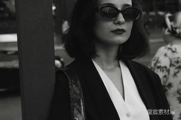 高清摄影 一个戴太阳镜的女人站在一根柱子旁边