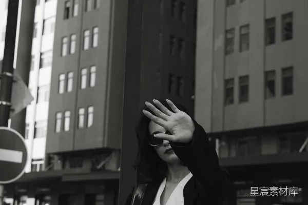 高清摄影 一个女人站在一栋高楼旁边的路上。