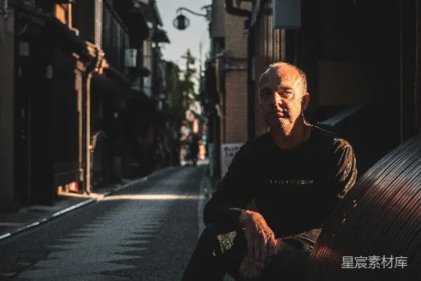高清摄影 黑色外套的男人在 sidewalk 上白天坐着