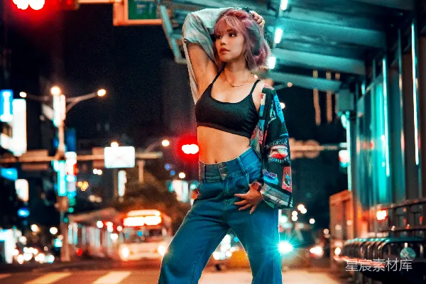 高清摄影 红背心和蓝色直筒牛仔裤的女人站在人行道上，夜间的景象。