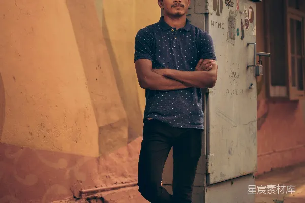 高清摄影 黑衣男子穿着黑色圆领T恤和黑色长裤站在棕色混凝土墙旁