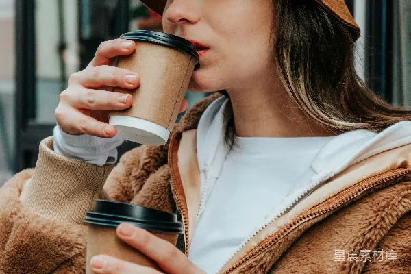 高清摄影 身穿棕色外套的女人手里拿着一个白色的陶瓷 mug