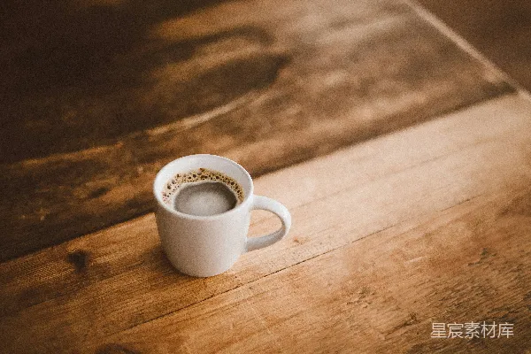 高清摄影 白色陶瓷小杯放在棕色木桌上，上面有咖啡。